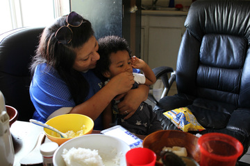 Alondra Ruiz feeds her grandson Gregory while visiting with Win La Bar's family during afternoon practice pick-up. Phoenix, Arizona, Sept. 18, 2015. (VOA/Victoria Macchi)