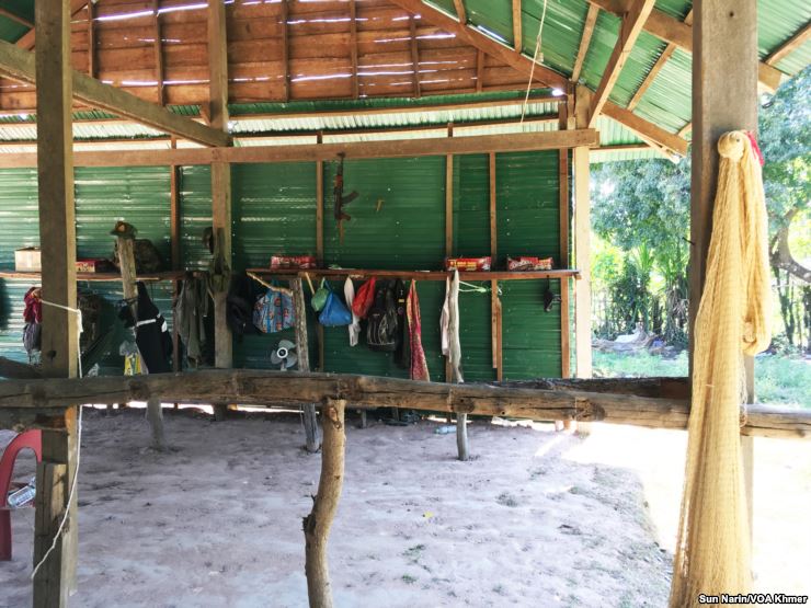 An AK-47 assault rifle and camouflage accessories hang inside the makeshift military base camp.