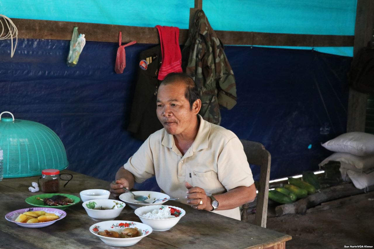 Man seated at table eats lunch.