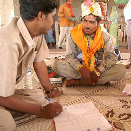 Photo of a counselor sitting on the floor, talking with a couple.