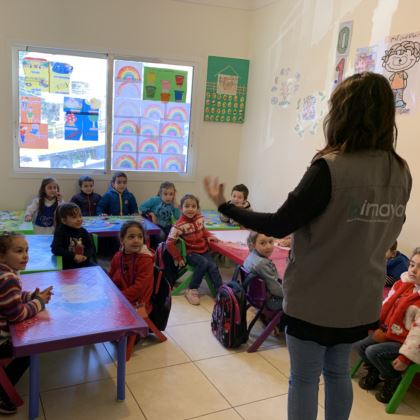 Photo of Syrian children in a classroom listening to a teacher.