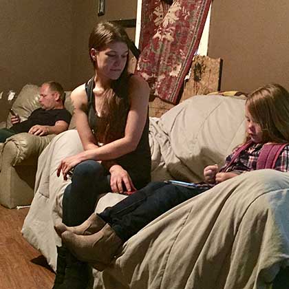 Photo of Katie Burns, center, sitting with her daughter on a couch.