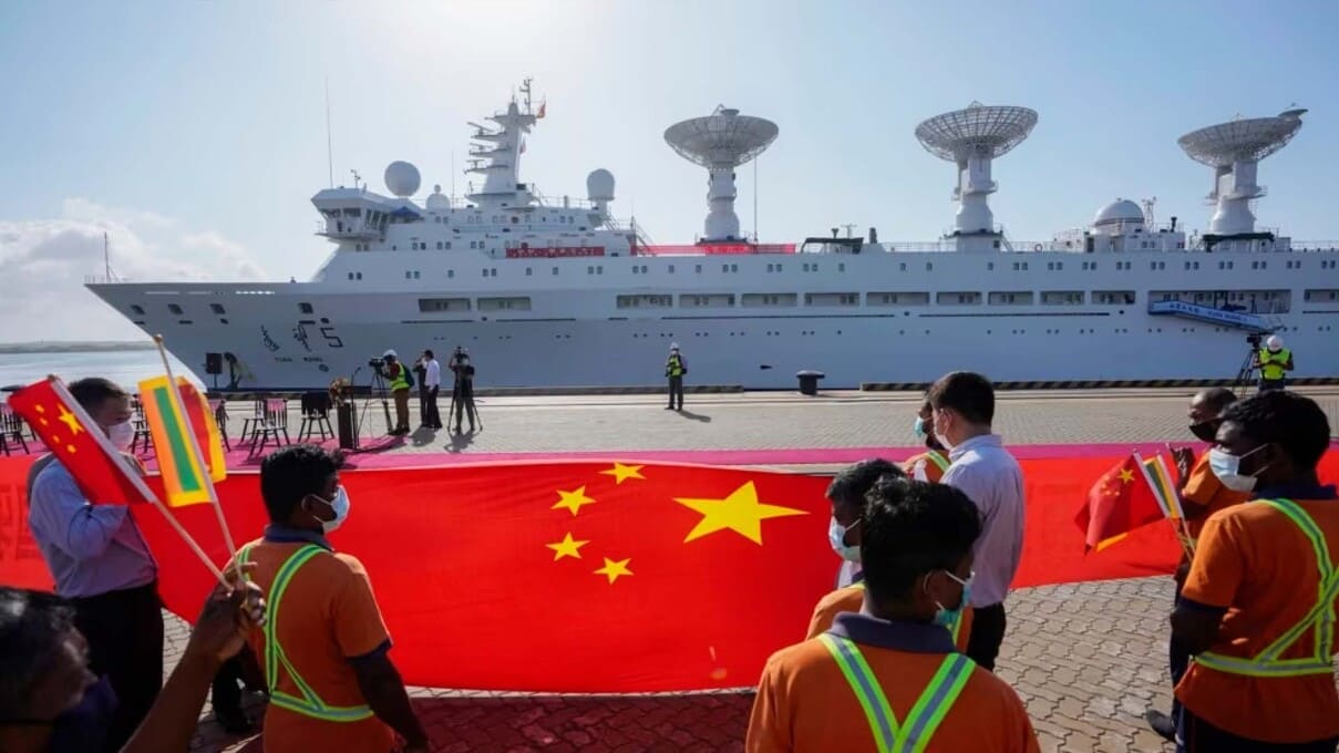 斯里兰卡港口工人在中国一带一路项目汉班托塔港手持中国国旗欢迎一艘中国考察船到港。（2022年8月16日）