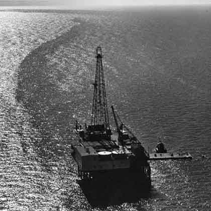 Black and white archival aerial photograph of an offshore oil rig.