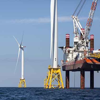 Photograph of three large wind turbines in the ocean.