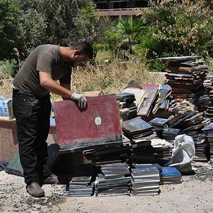 A volunteer stacks historical books rescued from the ashes of Mosul University’s destroyed Central Library in an area behind the building before being transported to a safer location. 