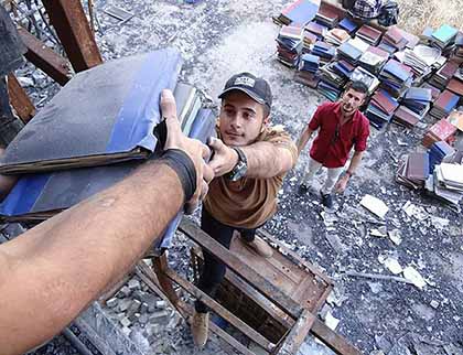 Mosul’s young volunteers moved dozens of books from inside Mosul University’s destroyed Central Library to an area outside the building.  