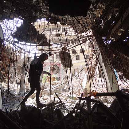 Tahany Saleh walks through a pile of debris at the gate of Mosul University’s Central Library as she works with her volunteer team to rescue books in the burned building.  