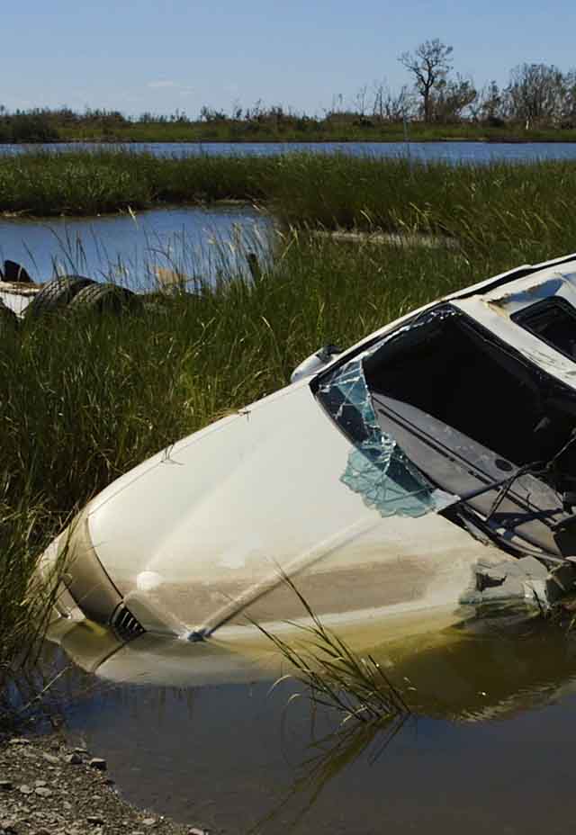 Photo of a wrecked car half submerged in water after a hurricane.