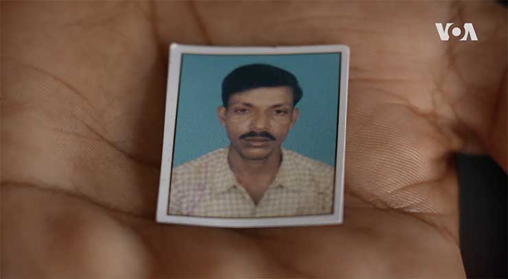 Closeup photo of a hand holdig a small portrait of Lolita's deceased husband, Sekhar.