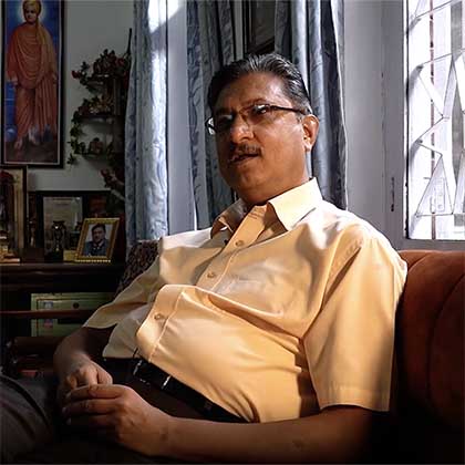 Screenshot portrait of Dr. Prakash Raj Regmi sitting on a couch by a window in an office.